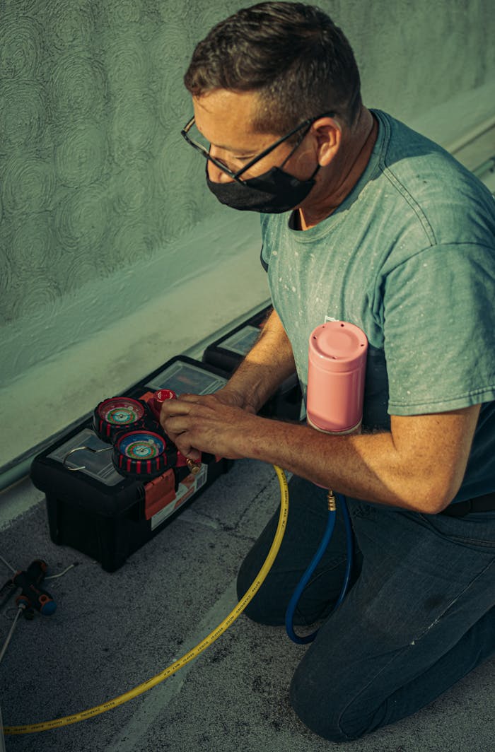 portfolio-01 A technician kneels outdoors, performing HVAC maintenance using specialized tools, enhancing system performance.
